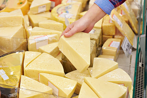 istock Hand with piece of cheese in store 516110300
