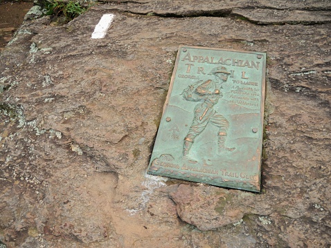 Springer Mountain, Georgia, USA - September 11, 2014: Close up of sign for the Appalachian Trail. Metal sign embedded in rock next to White Blaze mark at the top of Springer Mountain in northern Georgia at the trail head or start to the southern terminus of the Appalachian Trail.