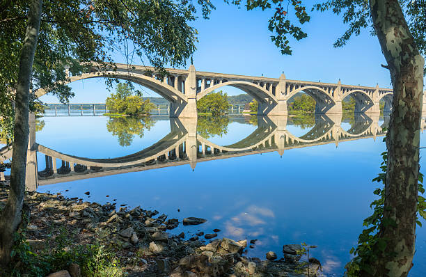 columbia-wrightsville bridge, céu azul refletido no rio susquehanna - arch bridge imagens e fotografias de stock