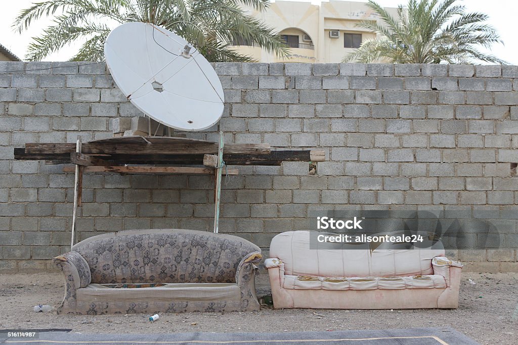 Worn sofas on a sports court, Dibba, United Arab Emirates Worn sofas sit below a satellite dish in a dusty sports court, Dibba, United Arab Emirates Abandoned Stock Photo