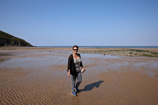 Mature hispanic woman walking on the seashore