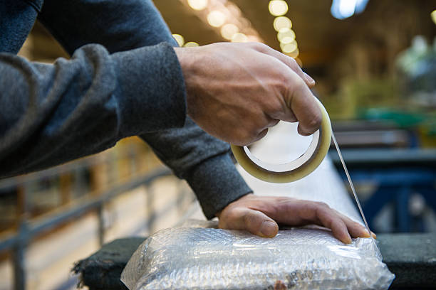 hombre trabajando en un almacén - packaging tape fotografías e imágenes de stock