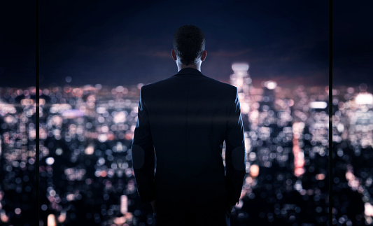 Close up of young successful businessman looking at the the city at night
