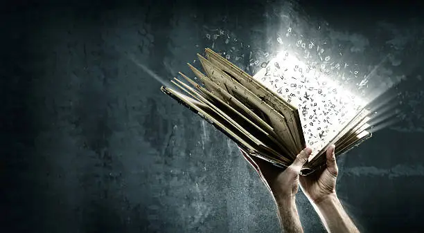 Holding magic book with flying letters