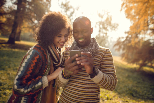 istock Smiling African American couple in nature using cell phone. 516135820