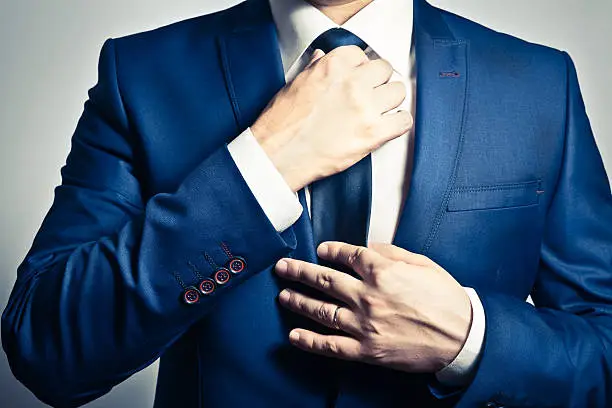 Businessman in blue suit adjusting his tie