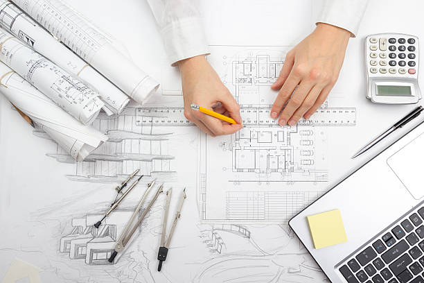 Architect working on blueprint. Architects workplace - architectural project, blueprints Architect working on blueprint. Architects workplace - architectural project, blueprints, ruler, calculator, laptop and divider compass. Construction concept. Engineering tools. architecture engineering stock pictures, royalty-free photos & images