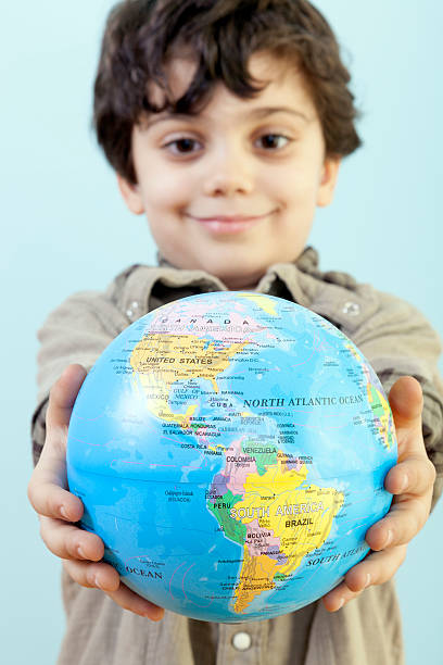 istock Happy Little Boy is Showing a Toy Globe Against Blue 516144160