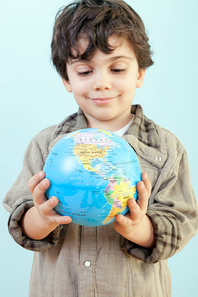 istock Little Boy is Looking to a Toy Globe Against Blue 516144276