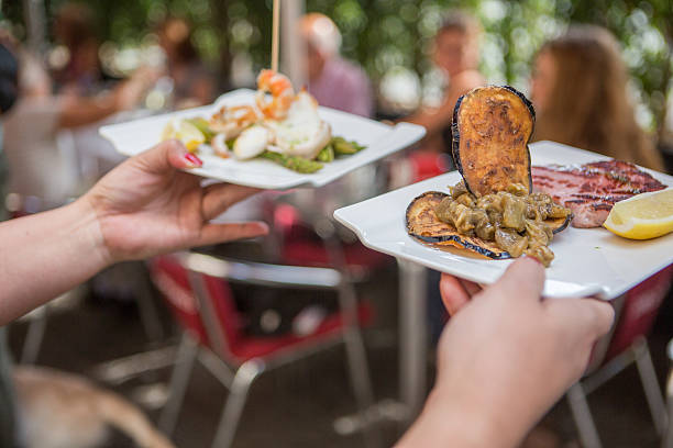 Barcelona, Spain - August 21, 2014: people eating at a tapas restaurant at La Boqueria market in Barcelona, Spain. Tapas is a traditional type of Spanish cuisine.