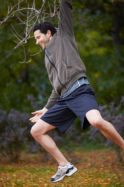 istock Man hanging from a tree in the park autumn smiling 516160021
