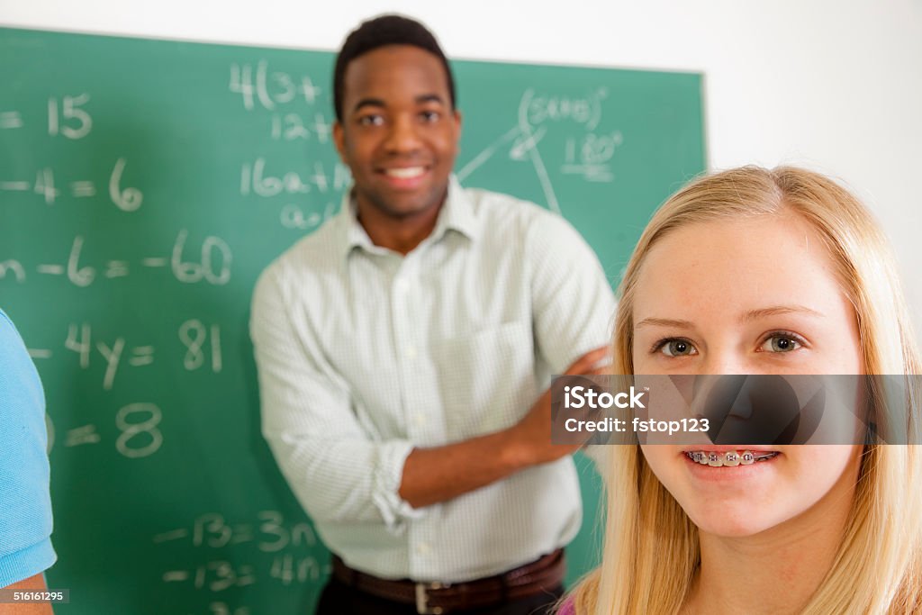 Education: Female student and teacher in school math class. Junior high school student and teacher in math class.  Student has braces. African-American Ethnicity Stock Photo