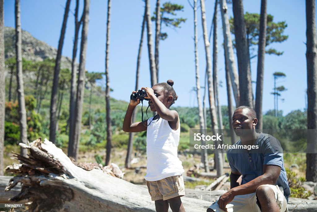 African girl looking through the binoculars African father sitting behind is daughter as she looks at something through the binoculars, cape town, western cape, south africa Africa Stock Photo