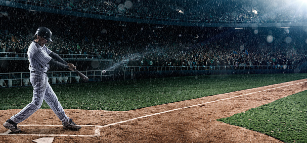 A moment of baseball game  on a baseball stadium under dramatic stormy skies and rain.