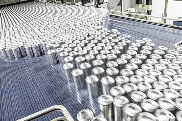 Aluminium cans moving along conveyor belt in processing plant Blurred motion of metal drinks cans being processed in industrial factory. Production line with abundance of containers moving at speed. aluminum plant stock pictures, royalty-free photos & images