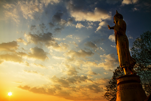 Sunrise and sculpture Buddha stand side with sky at country of Nan, Thailand