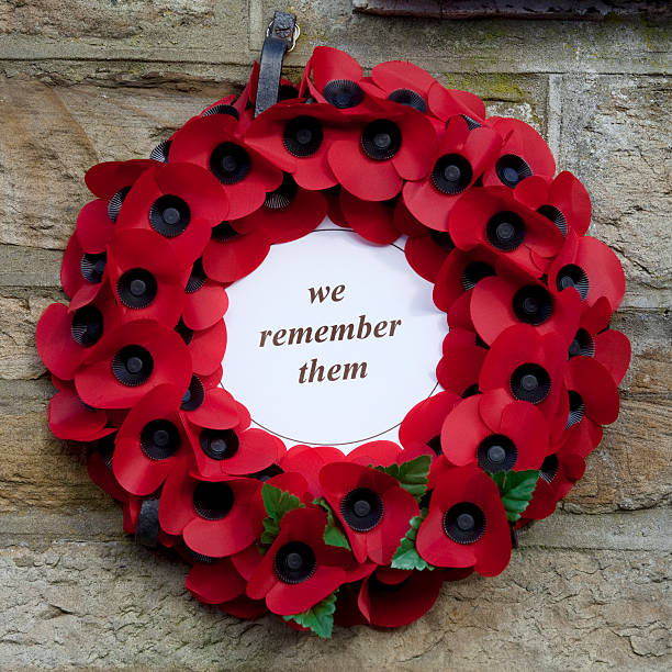 St. John's Chapel, England - March 07, 2016: A remembrance wreath made of artificial poppies mounted on a wall at the War Memorial in the village of St. John's Chapel in County Durham, England.  Poppies are the emblem of Remembrance Day, the 11th of November, which was Armistice Day in 1918, marking the end of World War One in Europe.  The poppy was chosen as the flower which bloomed first across some of the worst battlefields of the war, and has since come to represent the remembrance of all those in the allied armed forces who fought and died during both world wars and other conflicts.