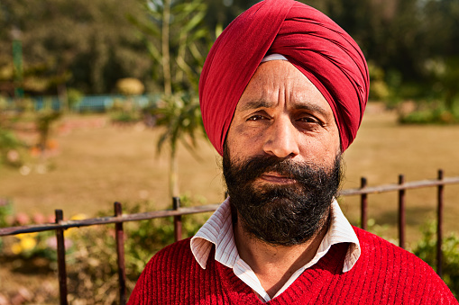 Portrait of Indian Sikh man near temple in New Delhi. A Sikh is a follower of Sikhism. Sikhism primarily originated in 15th century Punjab region of India. Sikhs are recognized by  their distinctively wrapped turban, uncut hair, beard and moustache, and they are supposed to wear an iron/steel bracelet.http://bem.2be.pl/IS/tea_plantations_380.jpg