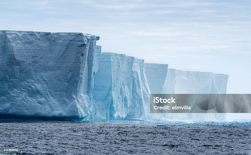 Tabular iceberg in Antarctica   Massive flat topped iceberg floating in the Southern Ocean of Antarctica showing the weathered cracks and fissures on the sides  Antarctica Stock Photo