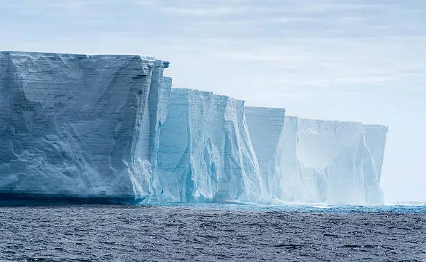   Massive flat topped iceberg floating in the Southern Ocean of Antarctica showing the weathered cracks and fissures on the sides 