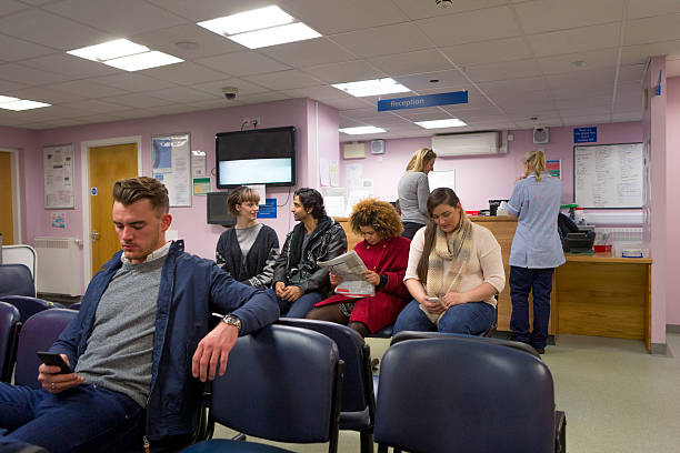 Patients in a Waiting room A mixed group of people can be seen waiting in a health clinic to be seen by the doctor. It is a typical British waiting room. waiting room stock pictures, royalty-free photos & images