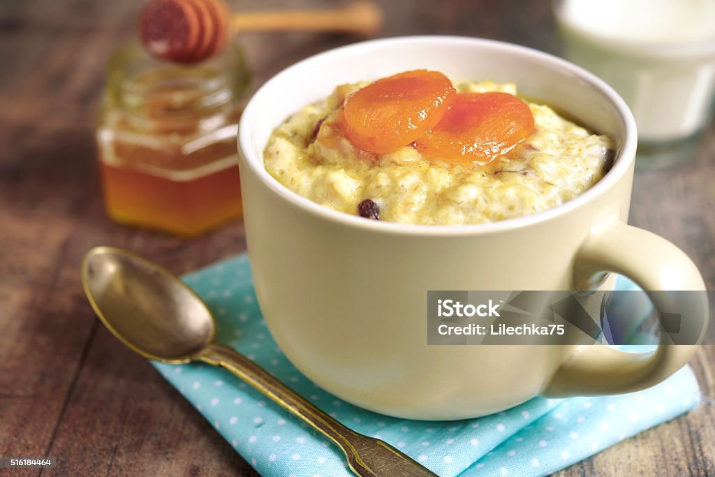 Oat porridge with honey, raisins and dried apricots. Oat porridge with honey, raisins and dried apricots on rustic background.Tinted photo. Apricot Stock Photo
