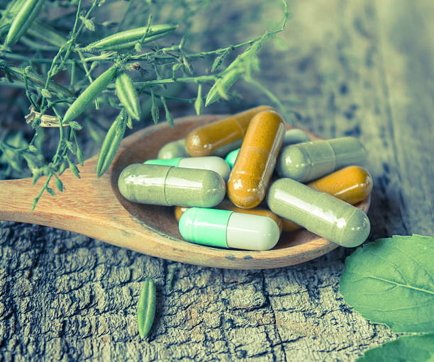 istock Herb capsule on wooden spoon with herb. 516186242