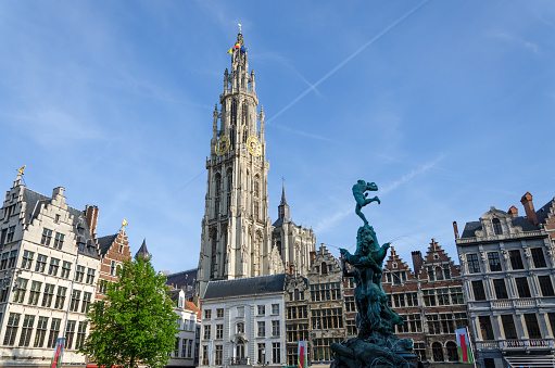 Statue of Brabo, throwing the giant's hand into the Scheldt River and the Cathedral of our Lady at Grand Place in Antwerp, Belgium.