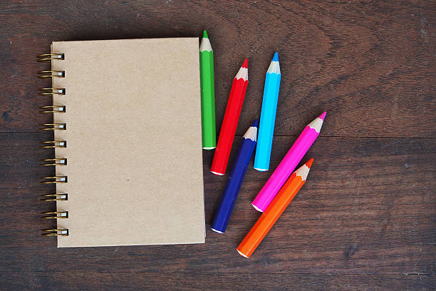 istock Close note book and color pencil on wooden background 516187024