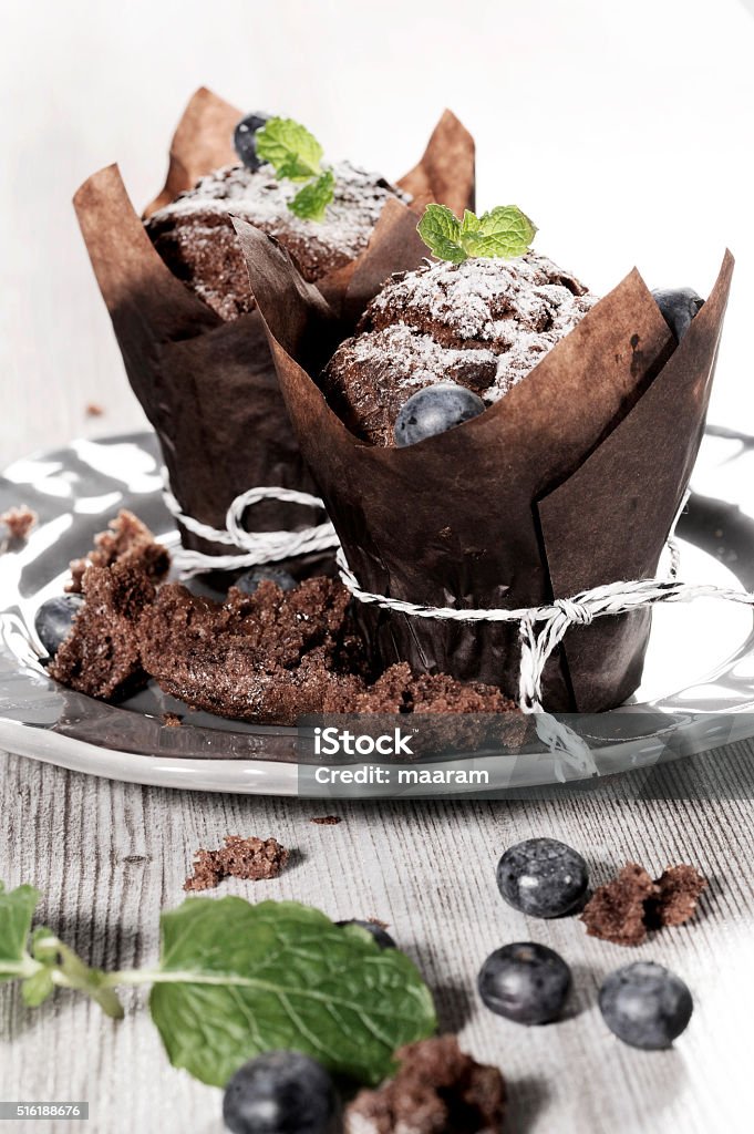 chocolate muffin with blueberry chocolate muffin with mint on a wooden backgroundchocolate muffin with blueberry on a wooden background Bakery Stock Photo