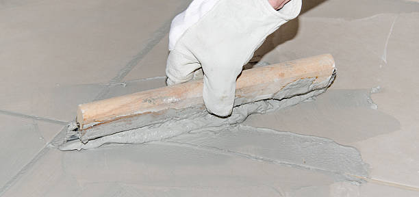 istock Tiler filling up joints with a rubber squeegee 516190047