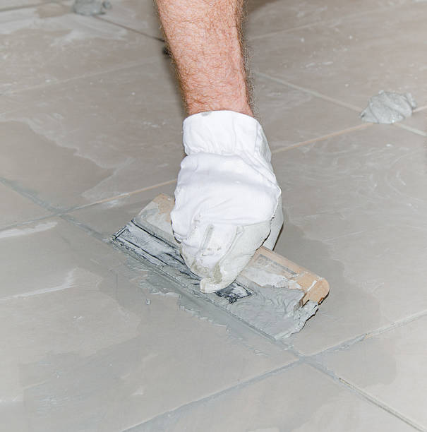 istock Tiler filling up joints with a rubber squeegee 516190051