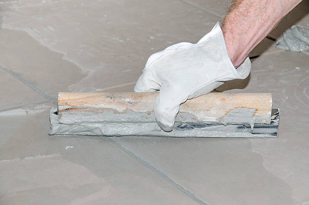 istock Tiler filling up joints with a rubber squeegee 516190053