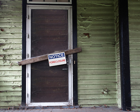 An old vacant house with Foreclosure sign on door