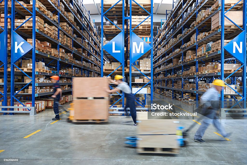 Coworkers carrying cardboard box in warehouse. Cardboard boxes on shelves in warehouse. Storhouse. Warehouse Stock Photo