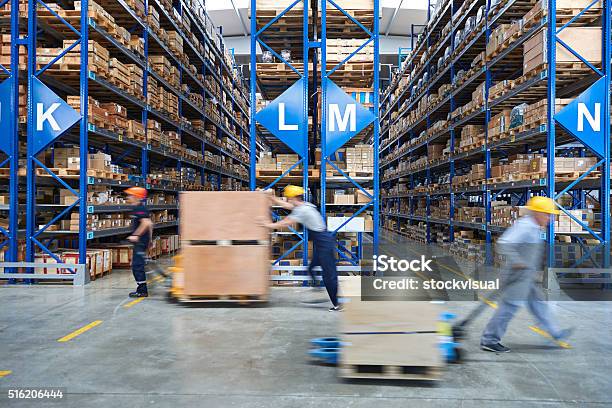 Coworkers Carrying Cardboard Box In Warehouse Stock Photo - Download Image Now - Warehouse, Freight Transportation, Distribution Warehouse