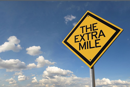 The extra mile yellow highway road sign