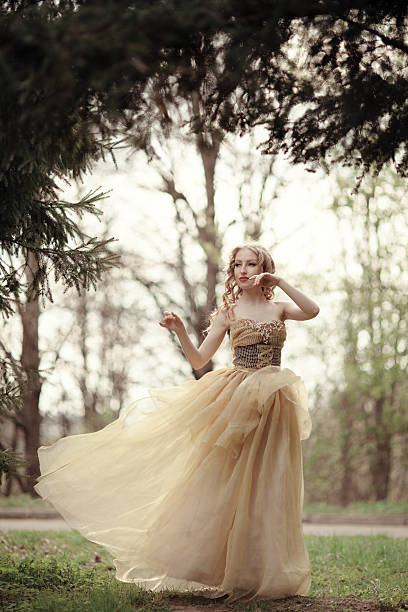 Attractive blond woman wearing a gold go-go dress posing in front of the camera and stroking her hair