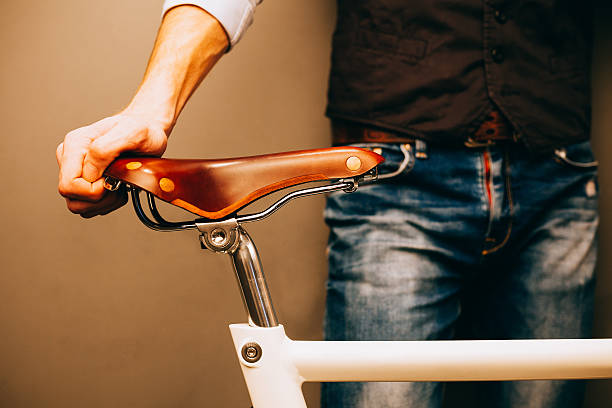 Close-up of young hipster man holding hands on his bicycle while standing indoors. Warm color. Hipster.