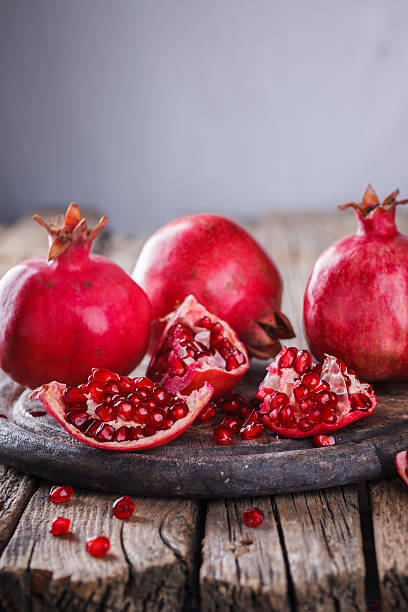 istock Juicy pomegranates,whole and broken on wooden background 516215508