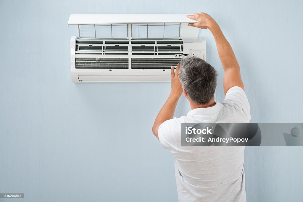 Man Cleaning Air Conditioning System Rear View Of A Man Cleaning Air Conditioning System Air Conditioner Stock Photo