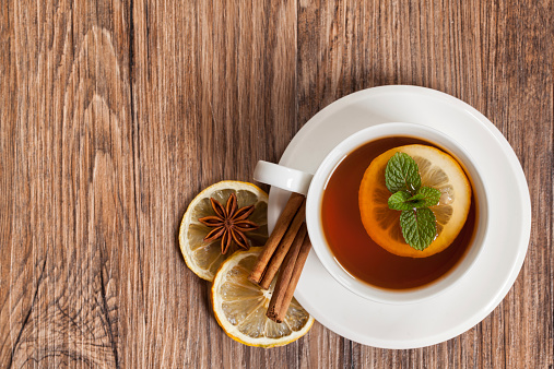 Mint tea with lemon and cinnamon on wooden background dark