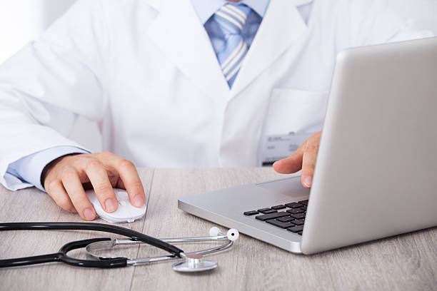 istock Midsection Of Doctor Using Laptop And Mouse At Desk 516216417