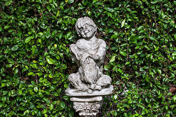 The boy, tired of playing on the street, leans against the stone wall. leaning against the corner, sulking and looking at the camera. Taken in daylight with a full frame camera.