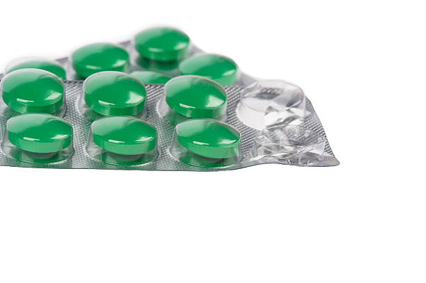 istock Green pills in blisters on white background 516231121
