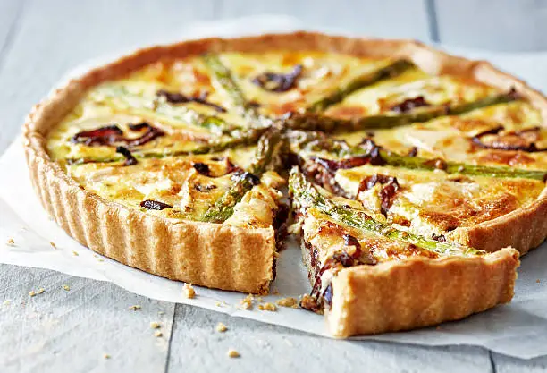 Photo of Asparagus quiche on white wooden surface