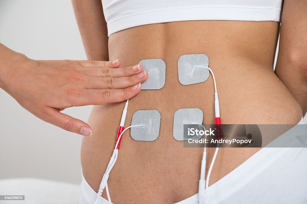 Therapist Placing Electrodes On Woman's Back Close-up Of Therapist Placing Electrodes On Woman's Back Electrode Stock Photo