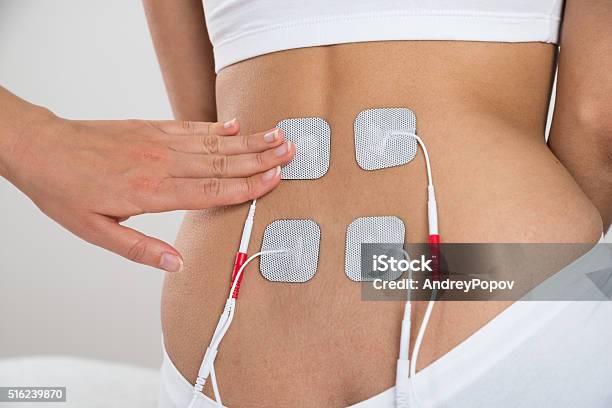 Therapist Placing Electrodes On Womans Back Stock Photo - Download Image Now - Electrode, Back, Rear View