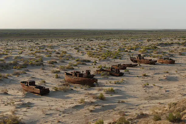 Rusty shells of former Aral Sea fishing fleet lying in the sand in Monyaq, Uzbekistan
