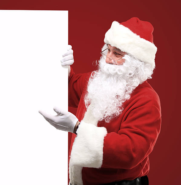 istock Santa Claus looking out from behind the blank sign 516248343